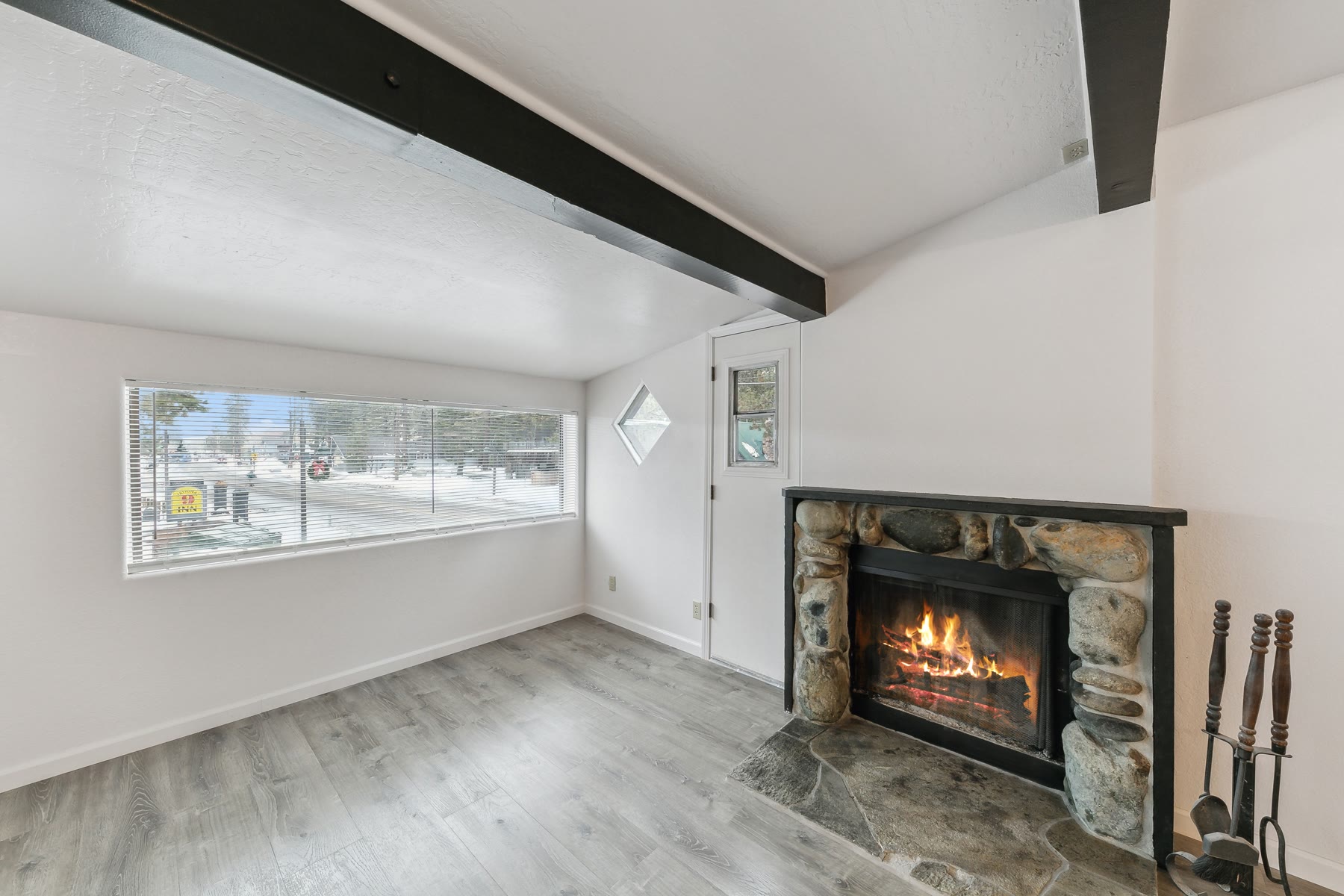 Remodeled apartment living room with a stone fireplace and a wide window