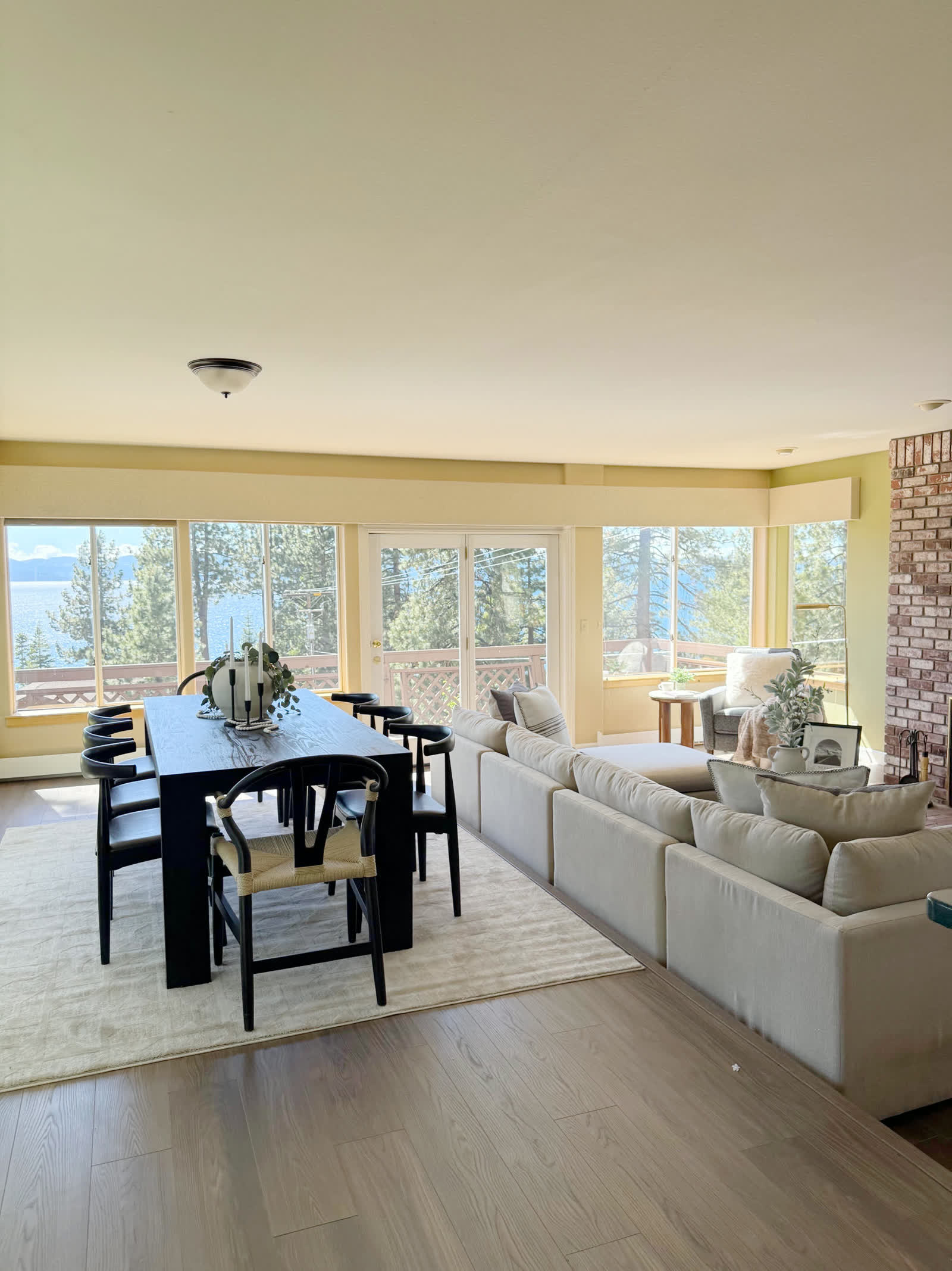 Staged dining and living room with lake views through a wall of windows