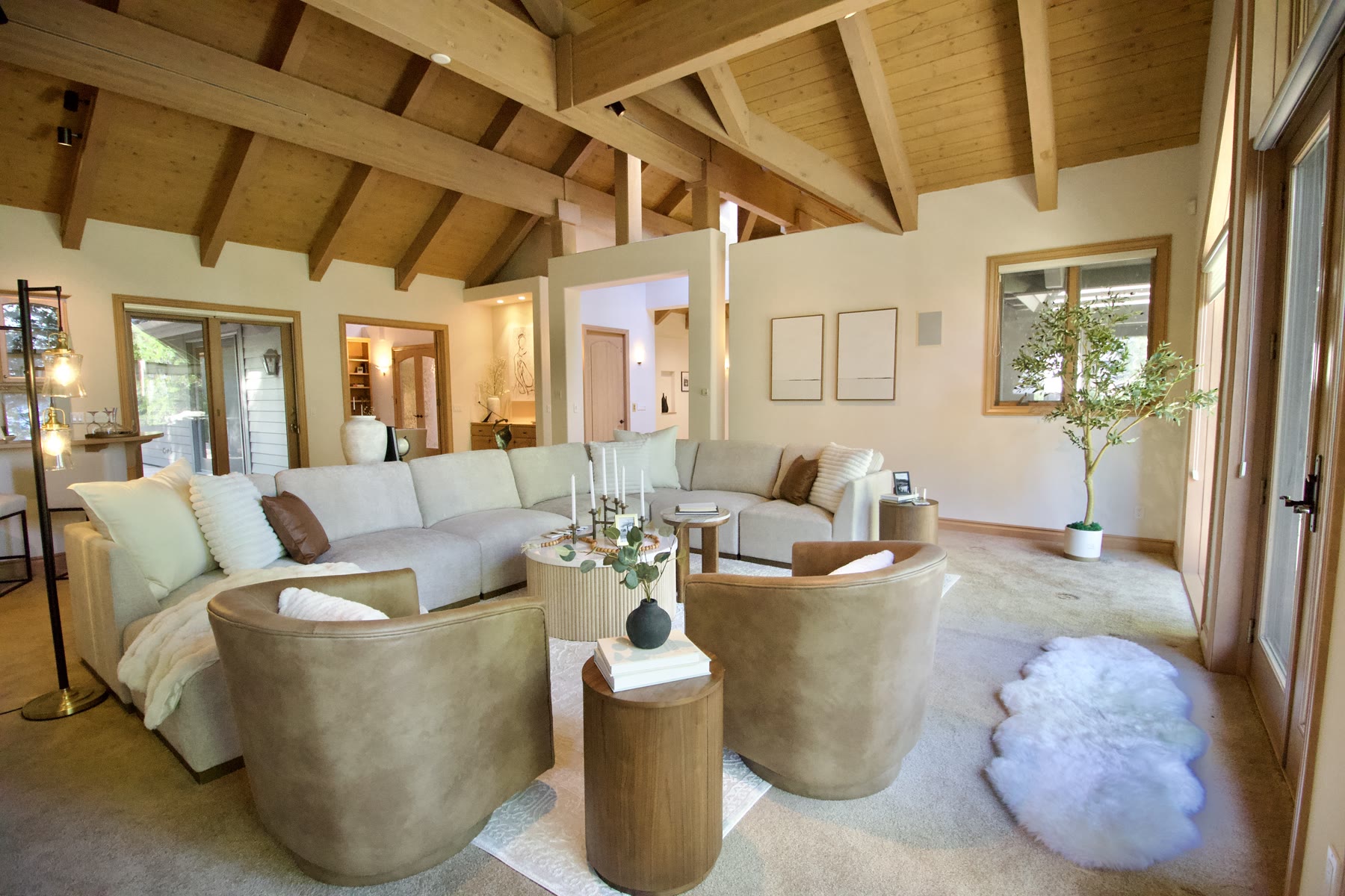 Staged great room with a cream sectional and leather swivel chairs under wood beams