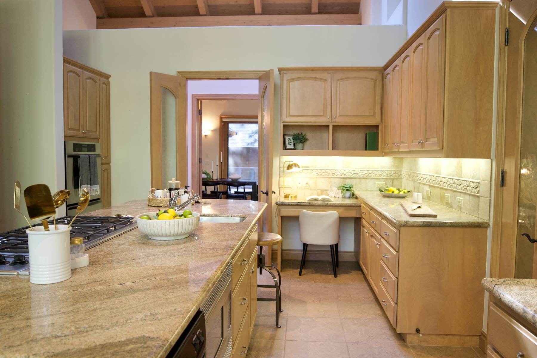 Staged kitchen with a stone island and a small desk nook