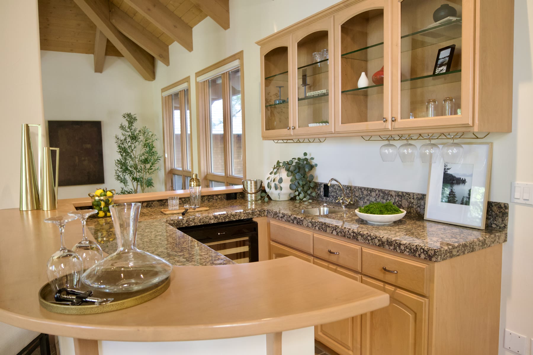 Staged bar with a decanter, glasses and greenery on the counter